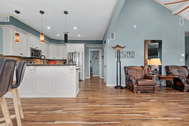 kitchen featuring appliances with stainless steel finishes, backsplash, pendant lighting, light hardwood / wood-style flooring, and white cabinets