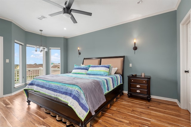 bedroom with hardwood / wood-style flooring, ceiling fan with notable chandelier, and ornamental molding