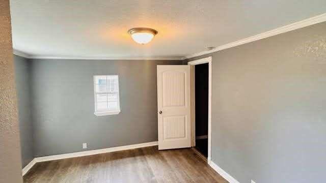 empty room with ornamental molding and dark wood-type flooring