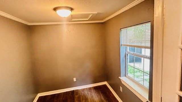 empty room with crown molding, plenty of natural light, and hardwood / wood-style flooring