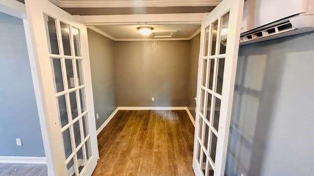 empty room with crown molding, french doors, and hardwood / wood-style floors