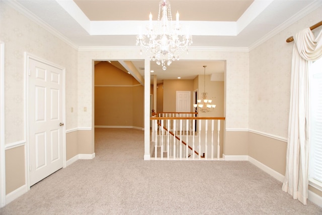 carpeted empty room featuring crown molding, a notable chandelier, and a tray ceiling