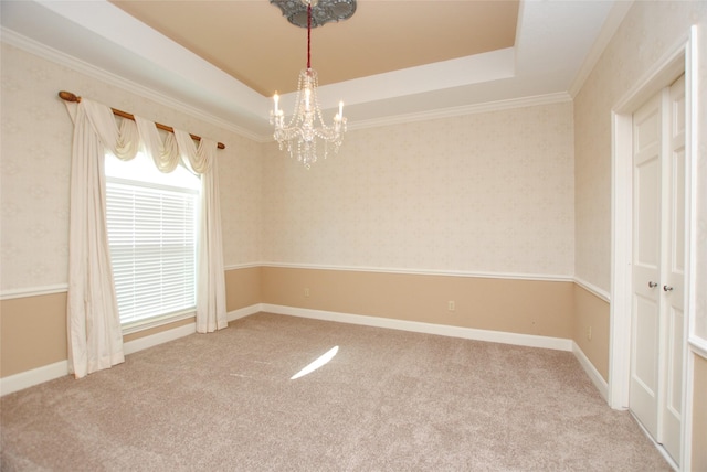 unfurnished room with crown molding, carpet flooring, a raised ceiling, and a notable chandelier