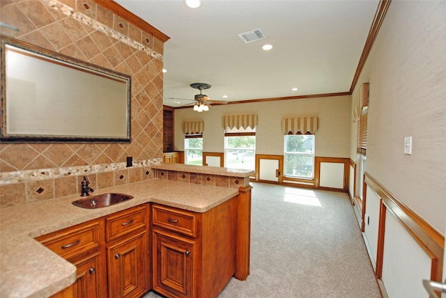 kitchen featuring sink, ornamental molding, decorative backsplash, light colored carpet, and kitchen peninsula