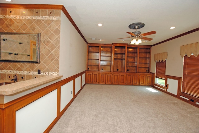 carpeted spare room featuring sink, ornamental molding, and ceiling fan