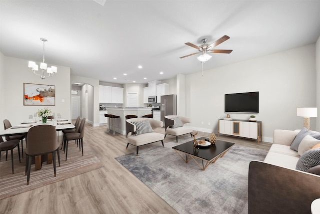 living room featuring light hardwood / wood-style flooring and ceiling fan with notable chandelier