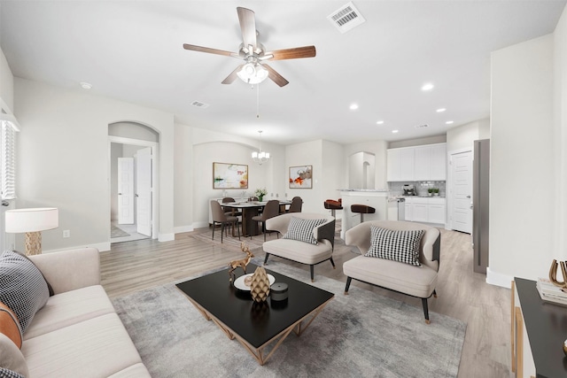 living room featuring light hardwood / wood-style flooring and ceiling fan with notable chandelier