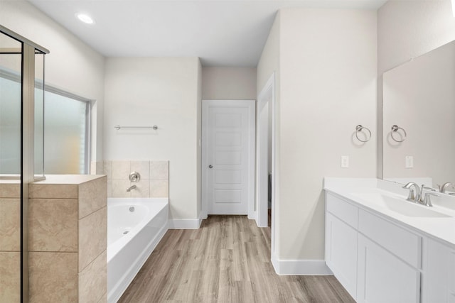 bathroom with vanity, wood-type flooring, and a bath