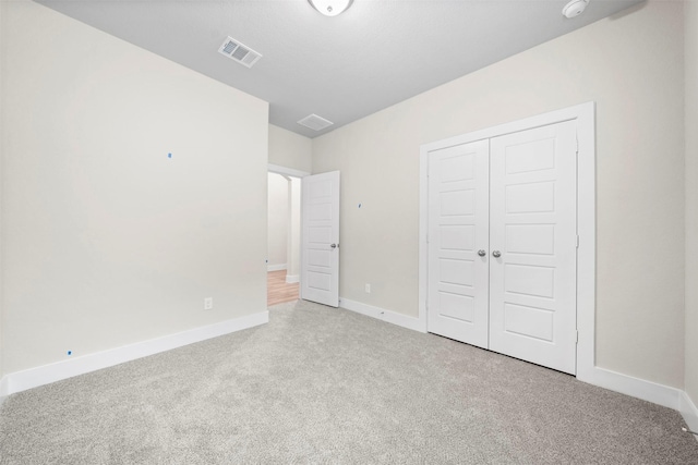 unfurnished bedroom featuring a closet and light colored carpet