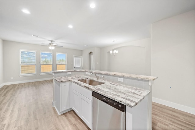 kitchen featuring pendant lighting, dishwasher, white cabinets, sink, and an island with sink