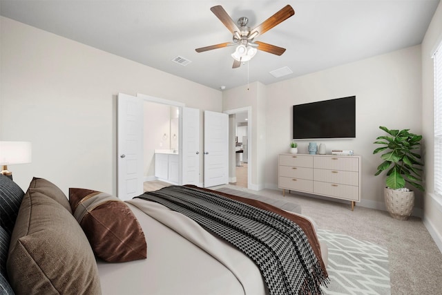 carpeted bedroom with ensuite bathroom and ceiling fan