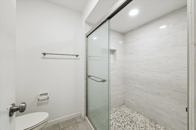 bathroom featuring tile patterned floors, toilet, and a shower with shower door