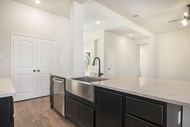 kitchen featuring hardwood / wood-style floors, dishwasher, sink, ceiling fan, and light stone counters