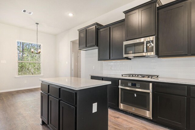 kitchen featuring a center island, pendant lighting, light hardwood / wood-style floors, decorative backsplash, and appliances with stainless steel finishes