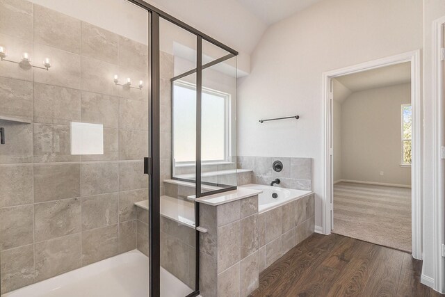 bathroom featuring wood-type flooring, shower with separate bathtub, a wealth of natural light, and lofted ceiling