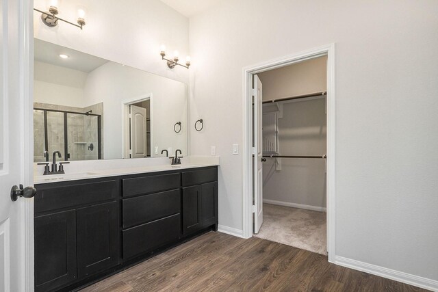 bathroom with hardwood / wood-style floors, vanity, and a shower with shower door