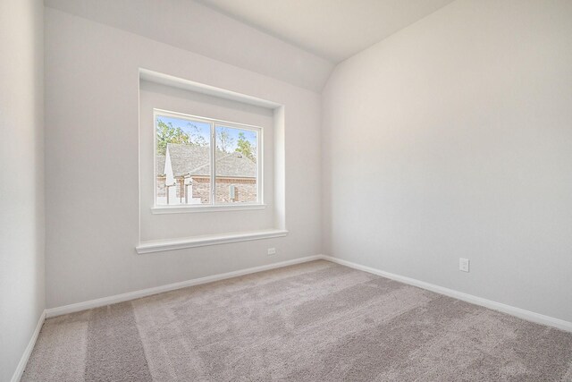 carpeted spare room with lofted ceiling