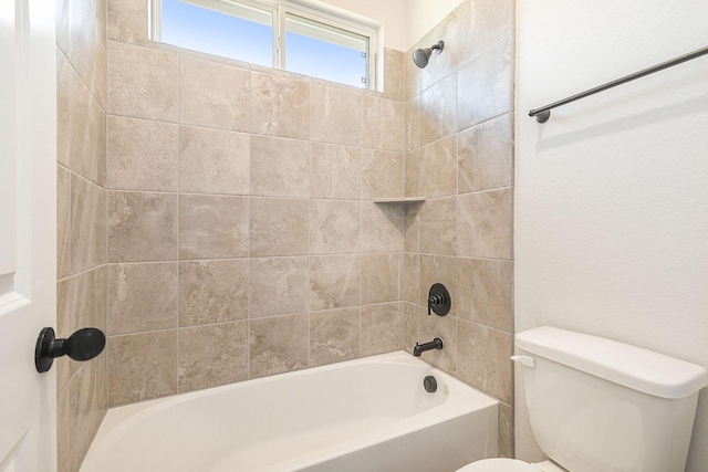 bathroom with tiled shower / bath combo and toilet