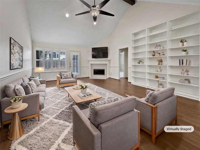 living room featuring beam ceiling, a tiled fireplace, ceiling fan, and hardwood / wood-style floors