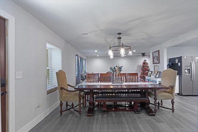 dining space with hardwood / wood-style floors and ceiling fan with notable chandelier