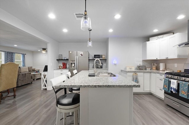 kitchen featuring light stone countertops, sink, stainless steel appliances, pendant lighting, and white cabinets