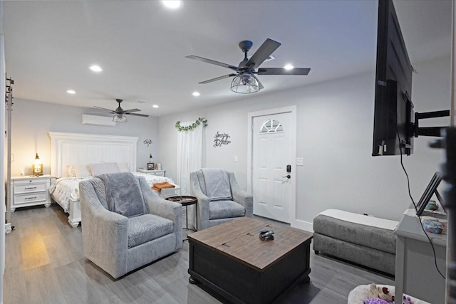 bedroom with a wall unit AC, ceiling fan, and hardwood / wood-style flooring