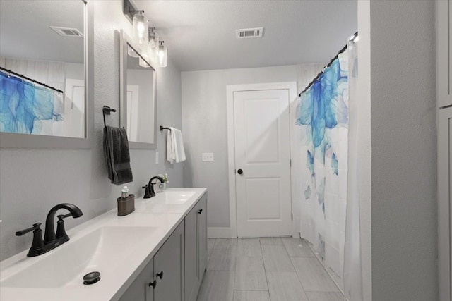 bathroom with curtained shower, vanity, and a textured ceiling