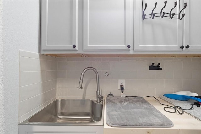 details featuring decorative backsplash, white cabinetry, and sink