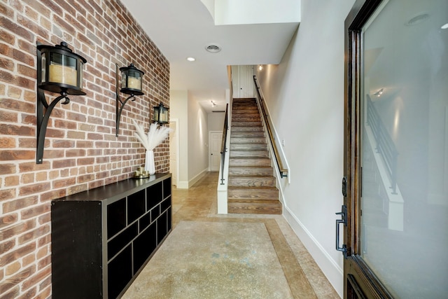 foyer entrance featuring brick wall