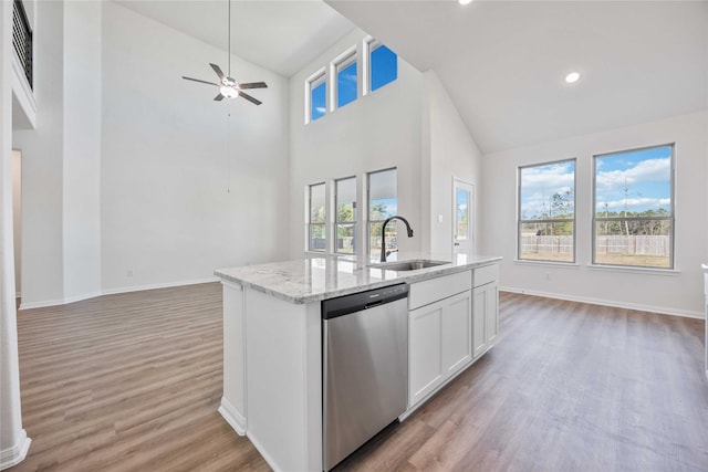 kitchen featuring ceiling fan, light stone counters, stainless steel dishwasher, a kitchen island with sink, and white cabinets