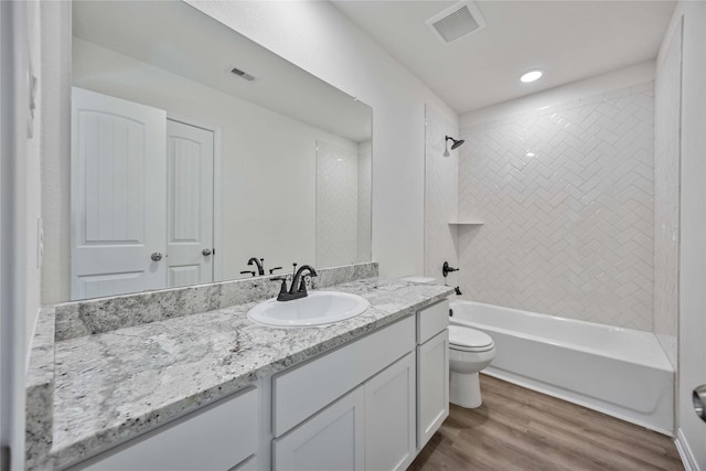 full bathroom with toilet, hardwood / wood-style floors, vanity, and washtub / shower combination