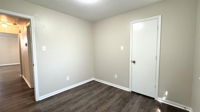 unfurnished room with dark wood-type flooring