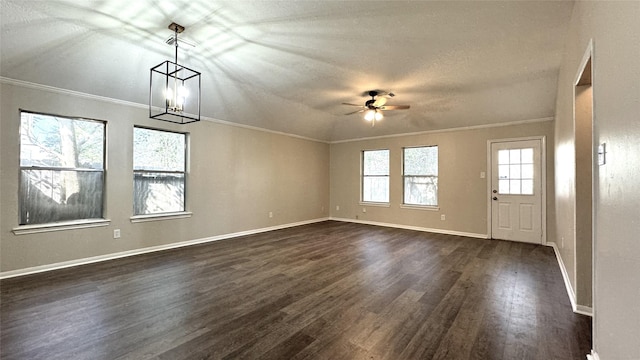 unfurnished living room with dark wood-type flooring, ceiling fan with notable chandelier, vaulted ceiling, ornamental molding, and a textured ceiling