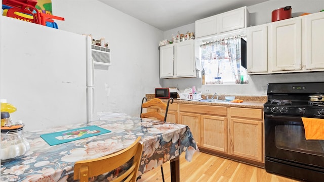 kitchen featuring black gas range, light brown cabinets, white refrigerator, sink, and light hardwood / wood-style flooring