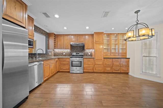 kitchen featuring ornamental molding, stainless steel appliances, sink, decorative light fixtures, and a chandelier