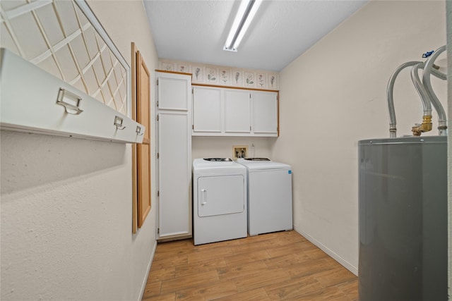 laundry area with washer and clothes dryer, cabinets, a textured ceiling, water heater, and light hardwood / wood-style floors