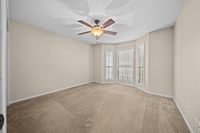 spare room featuring light carpet, ceiling fan, and a textured ceiling