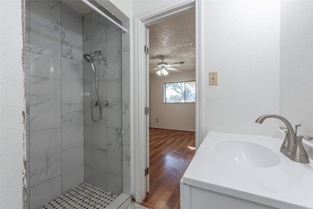 bathroom with vanity, ceiling fan, wood-type flooring, and tiled shower