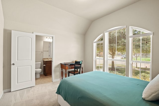 bedroom with connected bathroom, light colored carpet, and lofted ceiling