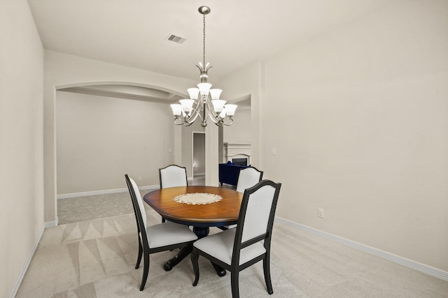 dining space featuring light carpet and a chandelier