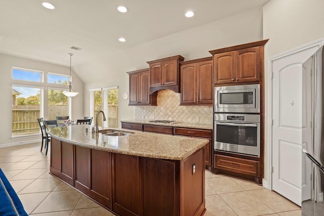 kitchen featuring sink, tasteful backsplash, light stone counters, light tile patterned flooring, and appliances with stainless steel finishes