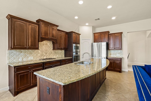 kitchen featuring light tile patterned flooring, sink, stainless steel appliances, and a kitchen island with sink