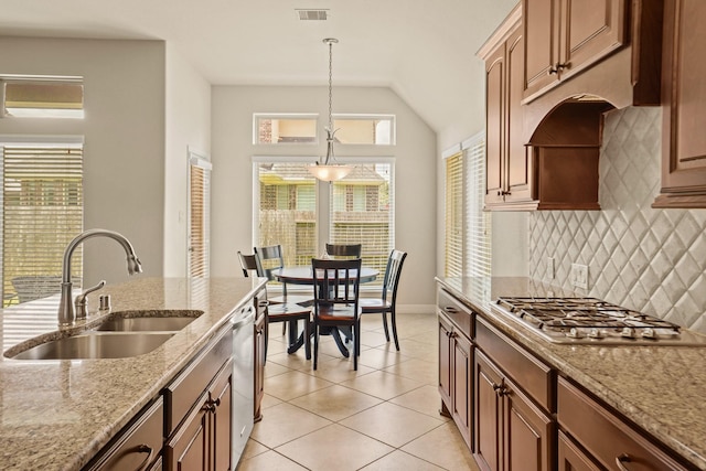 kitchen with backsplash, decorative light fixtures, light stone countertops, and sink