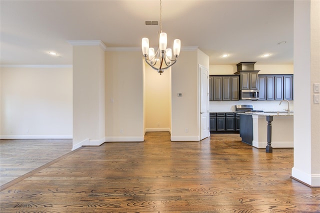 kitchen featuring stainless steel appliances, dark hardwood / wood-style flooring, a chandelier, decorative light fixtures, and ornamental molding