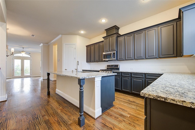 kitchen with a kitchen island with sink, french doors, a kitchen breakfast bar, ceiling fan, and appliances with stainless steel finishes