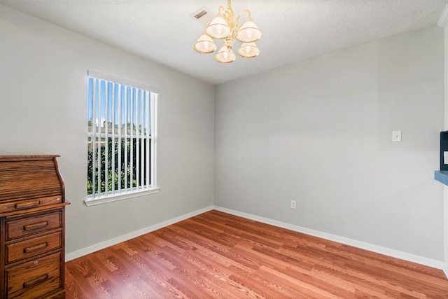 unfurnished room featuring hardwood / wood-style flooring and a notable chandelier