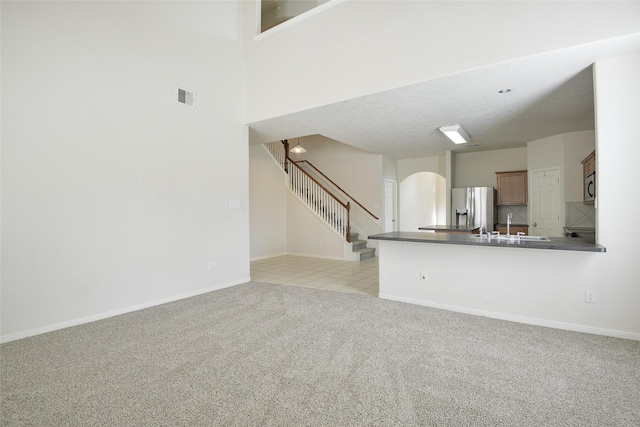 unfurnished living room with light colored carpet and sink