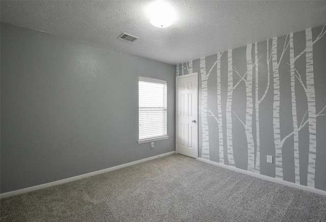 carpeted empty room with a textured ceiling