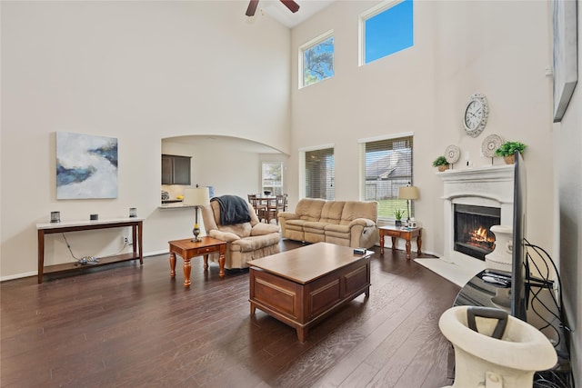 living room with ceiling fan, dark hardwood / wood-style floors, and a high ceiling