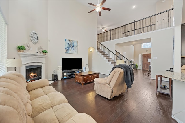 living room with ceiling fan, dark hardwood / wood-style flooring, and a high ceiling